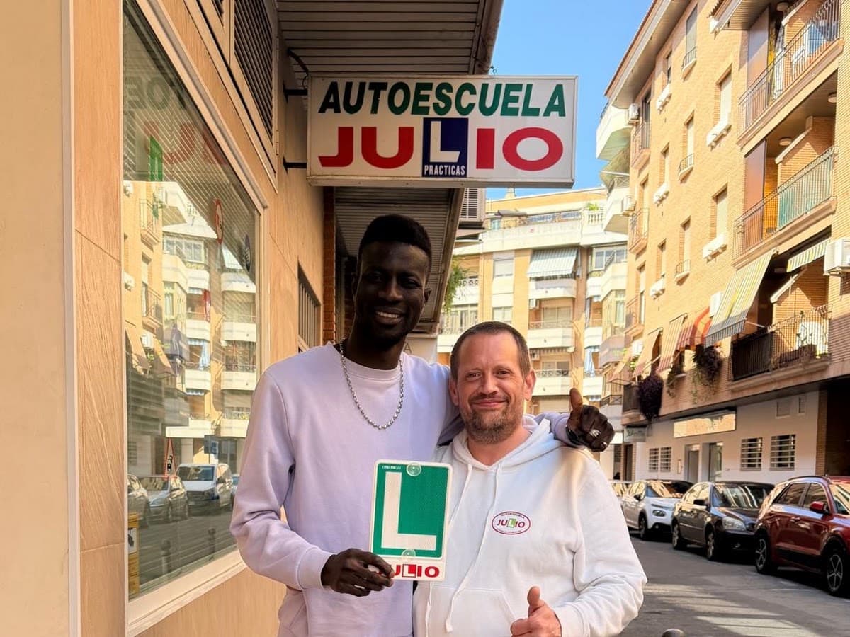 Saliou y Julio posan frente a la fachada de Autoescuela Julio